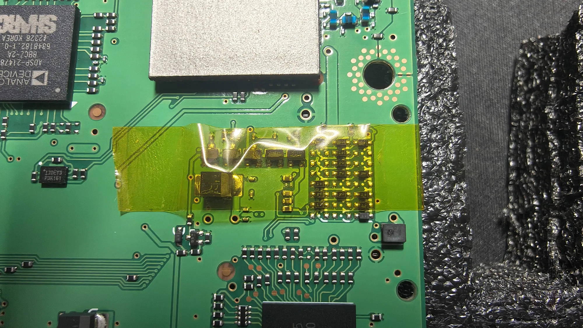 Primer intento de proteger la matriz: una tira de cinta kapton amarilla sobre la matriz, con una arruga grande y aire debajo en la parte de arriba.