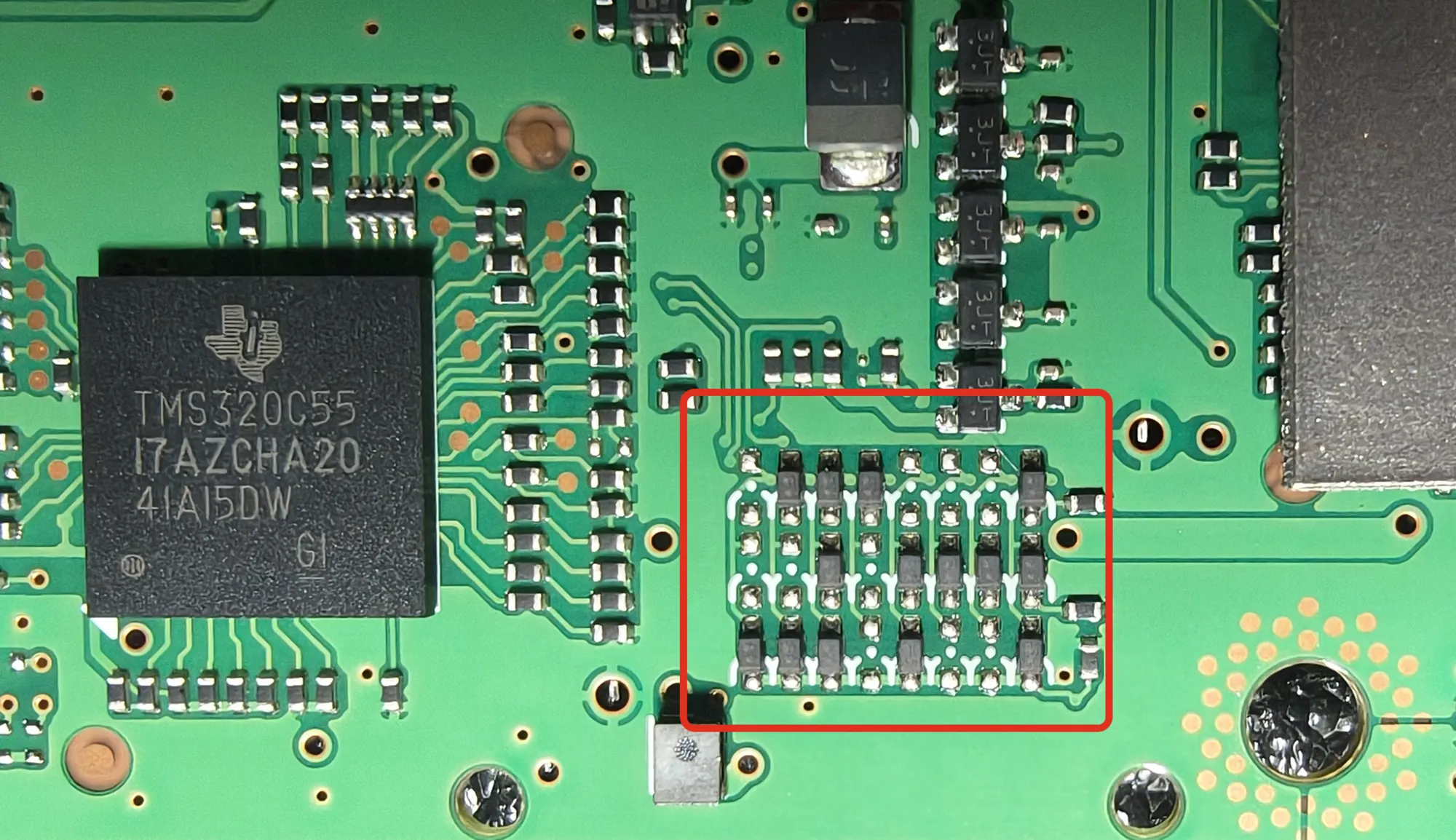 La cara de la placa con el DSP: a la izquierda el chip cuadrado negro rotulado TMS320C55, y a su derecha, dentro de un recuadro rojo, la matriz de diodos diminutos en tres filas, con un blindaje metálico grande a la derecha.